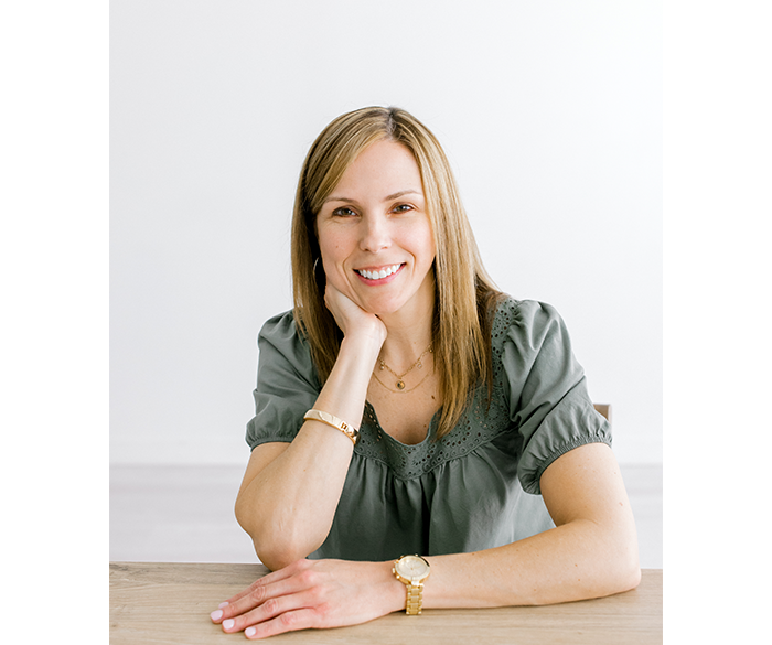 Kelly Dickerson smiling while leaning on a table