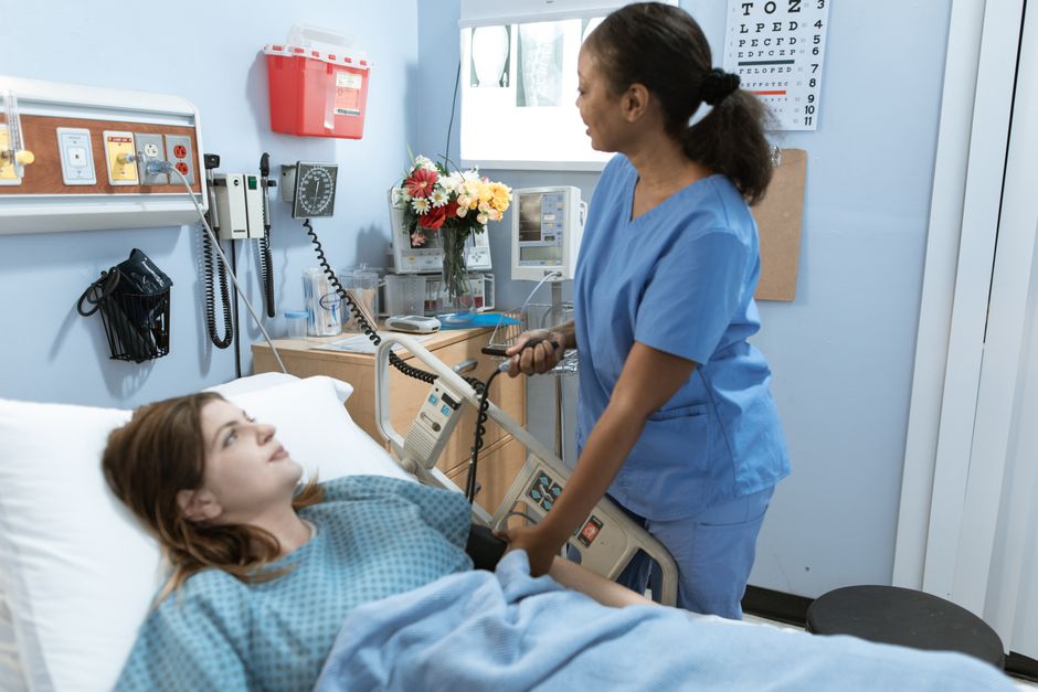 Patient resting in a hospital bed while a nurse provides care